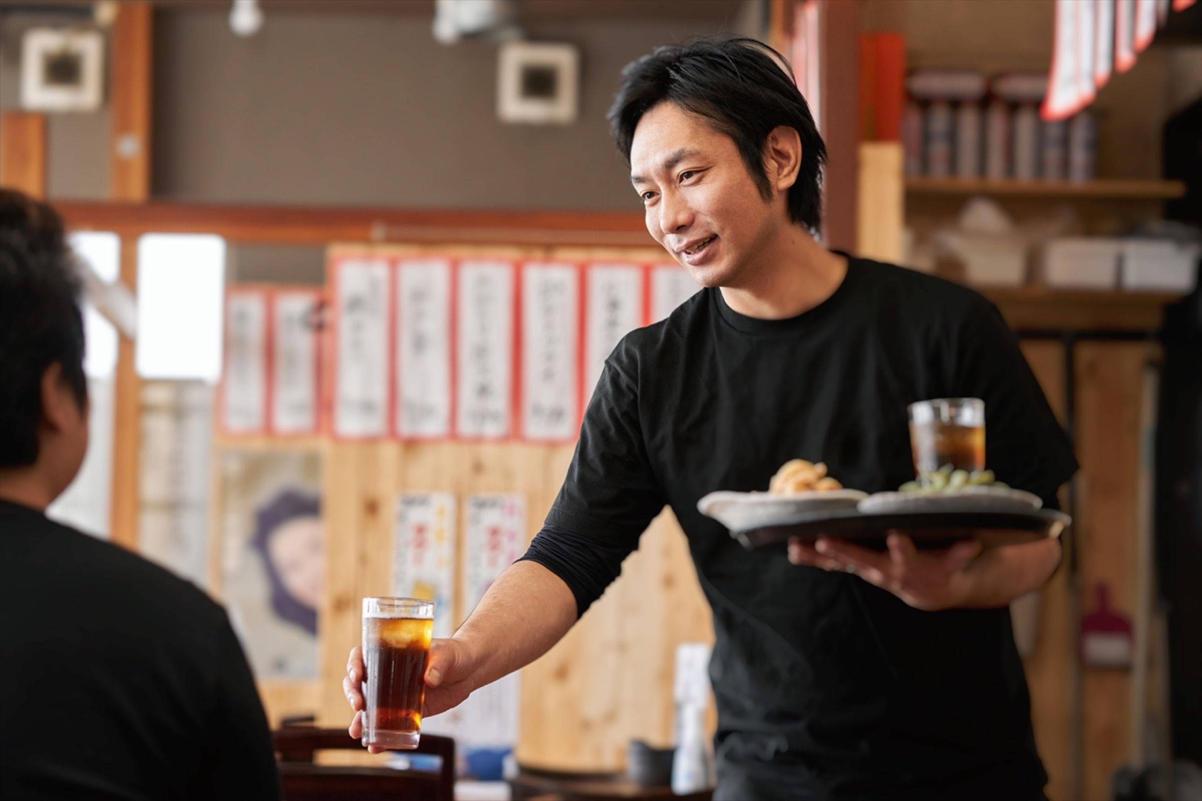 料理をお客様の席へ運ぶ飲食店のスタッフ